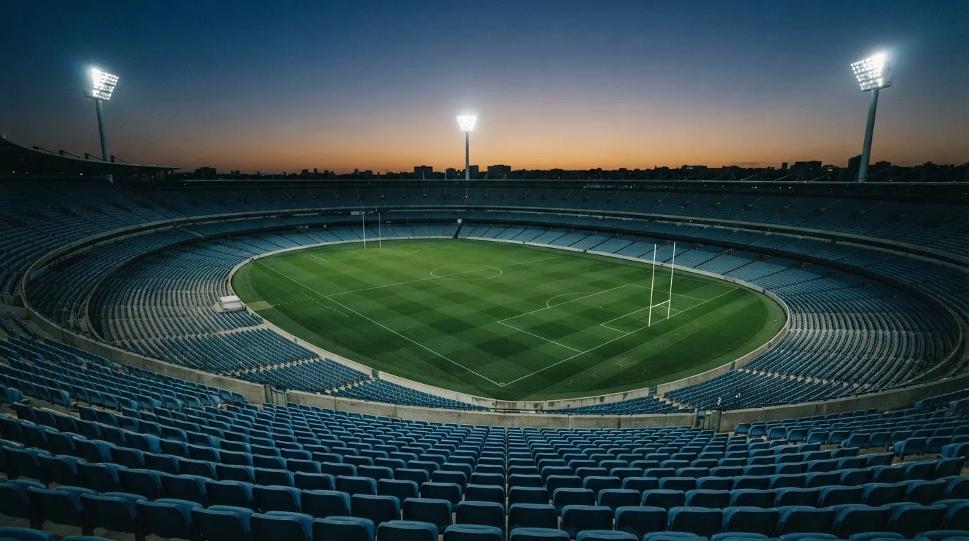 An empty football stadium with floodlight masts at dusk
