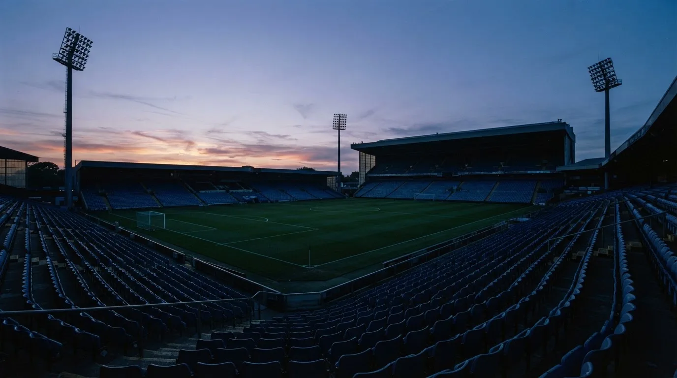 An empty football stadium with floodlight masts at dusk