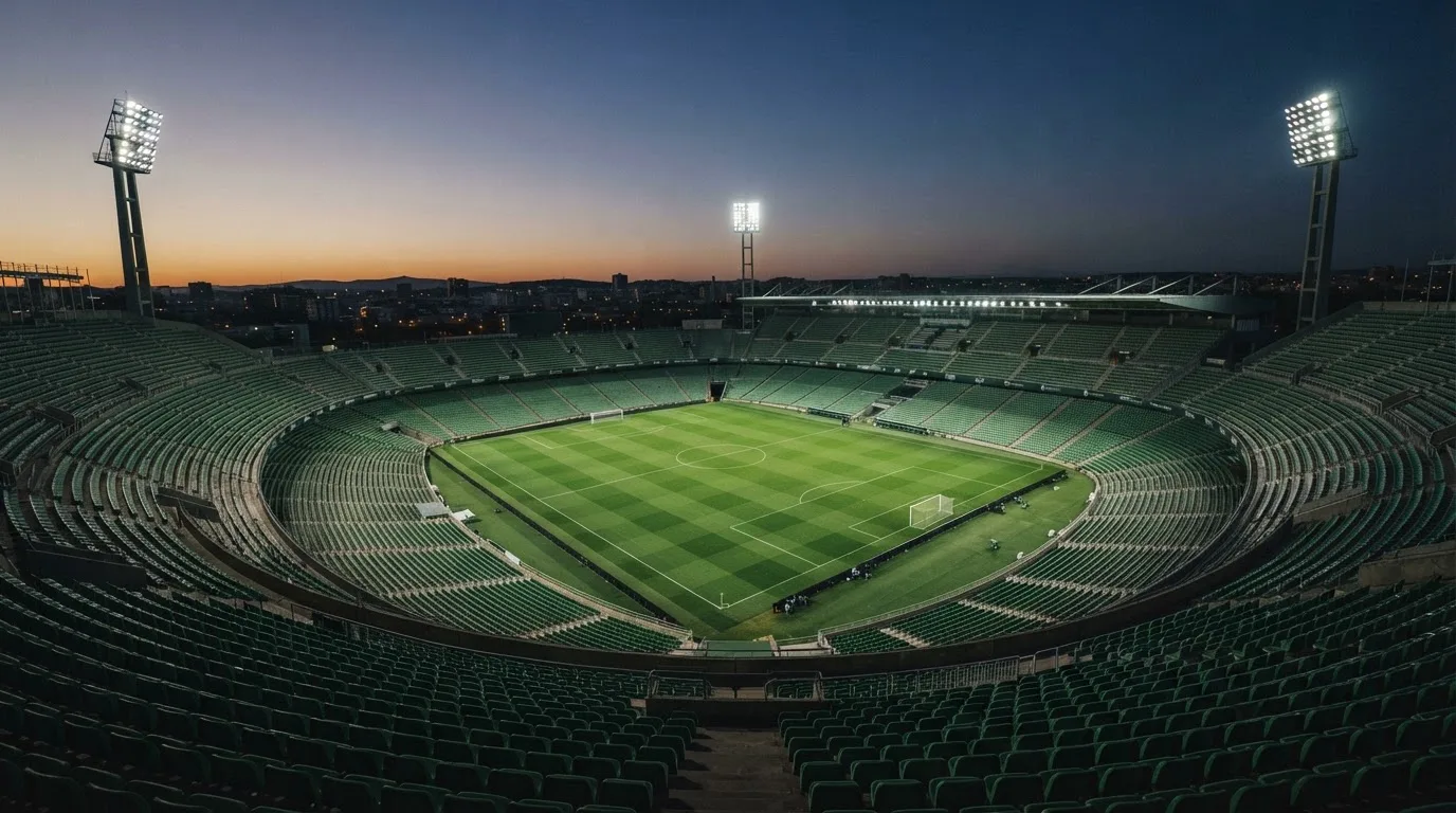An empty football stadium with floodlight masts at dusk