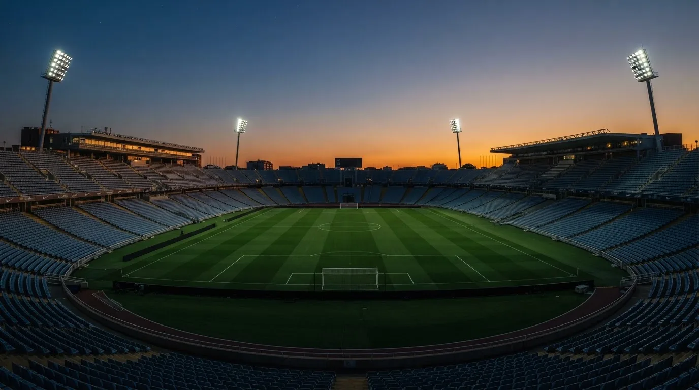 An empty football stadium with floodlight masts at dusk