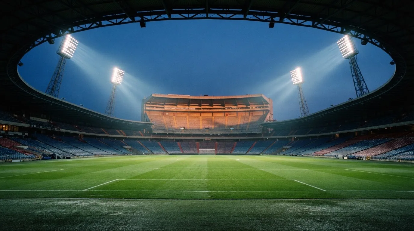 An empty football stadium with floodlight masts at dusk