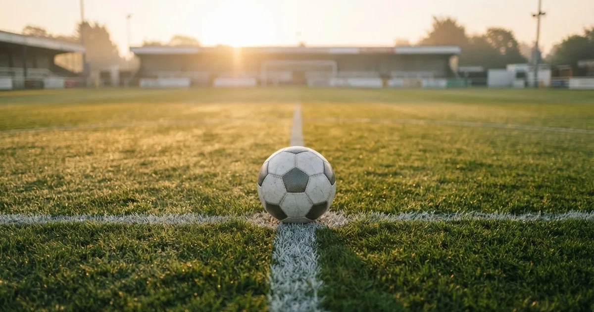 A ball on the centre spot of a grass pitch in morning light