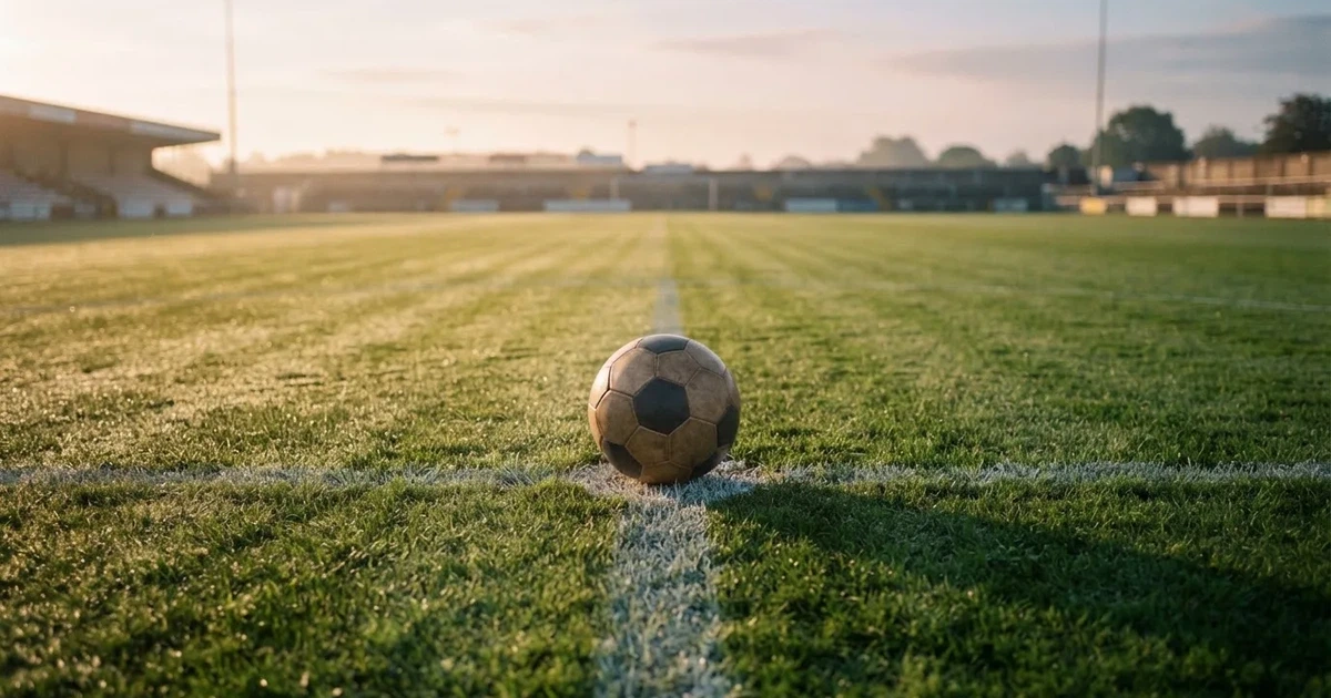 A ball on the centre spot of a grass pitch in morning light