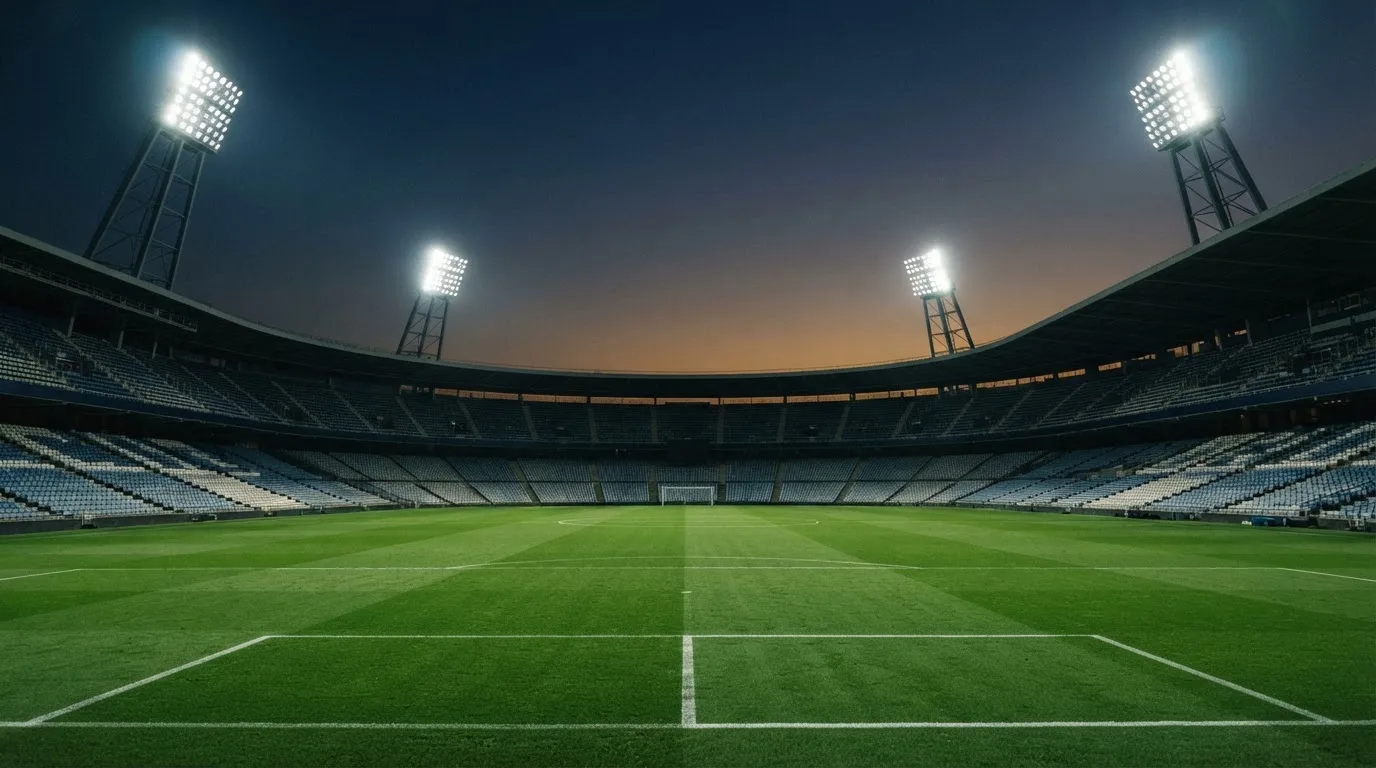 An empty football stadium with floodlight masts at dusk