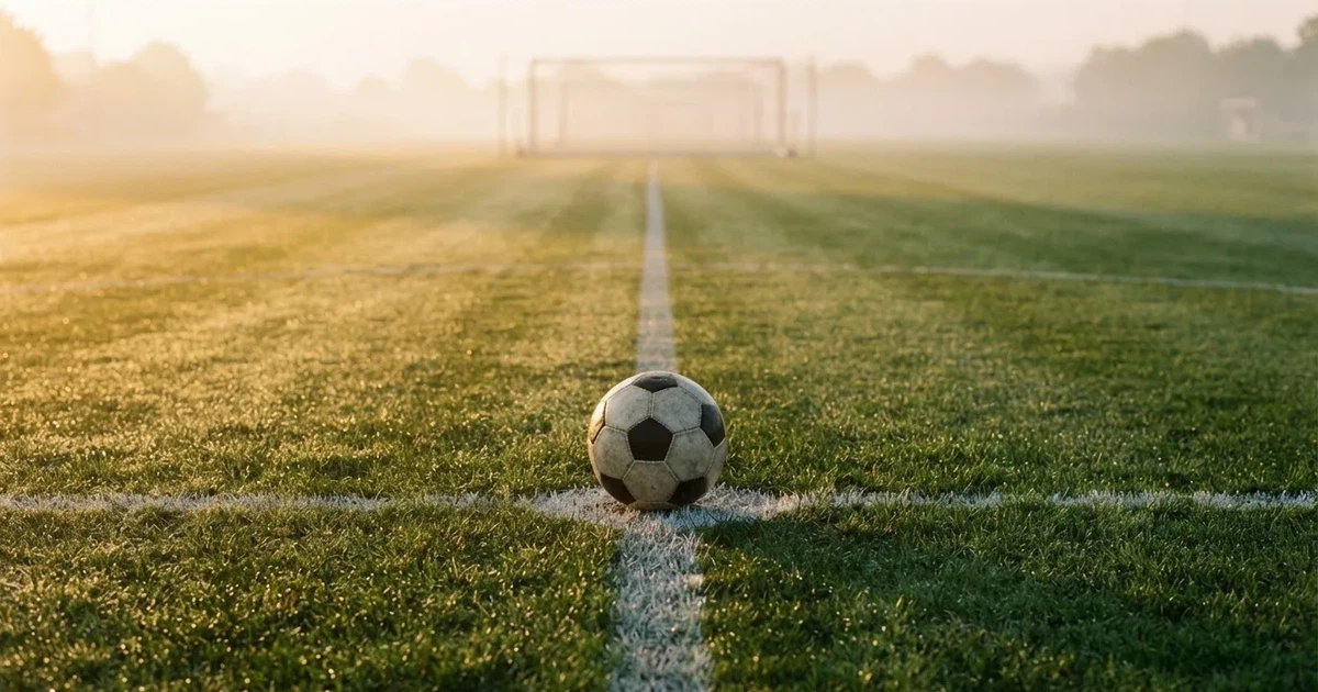 A ball on the centre spot of a grass pitch in morning light
