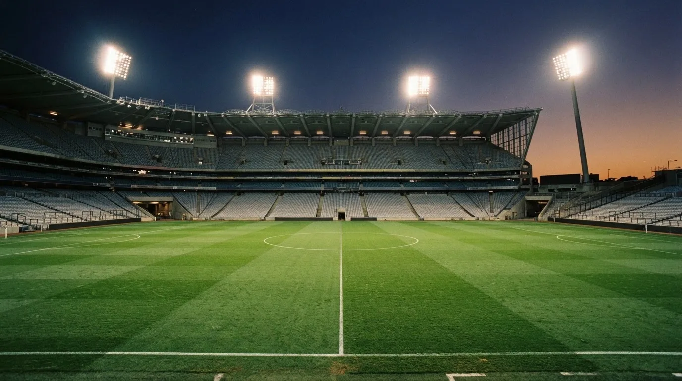 An empty football stadium with floodlight masts at dusk
