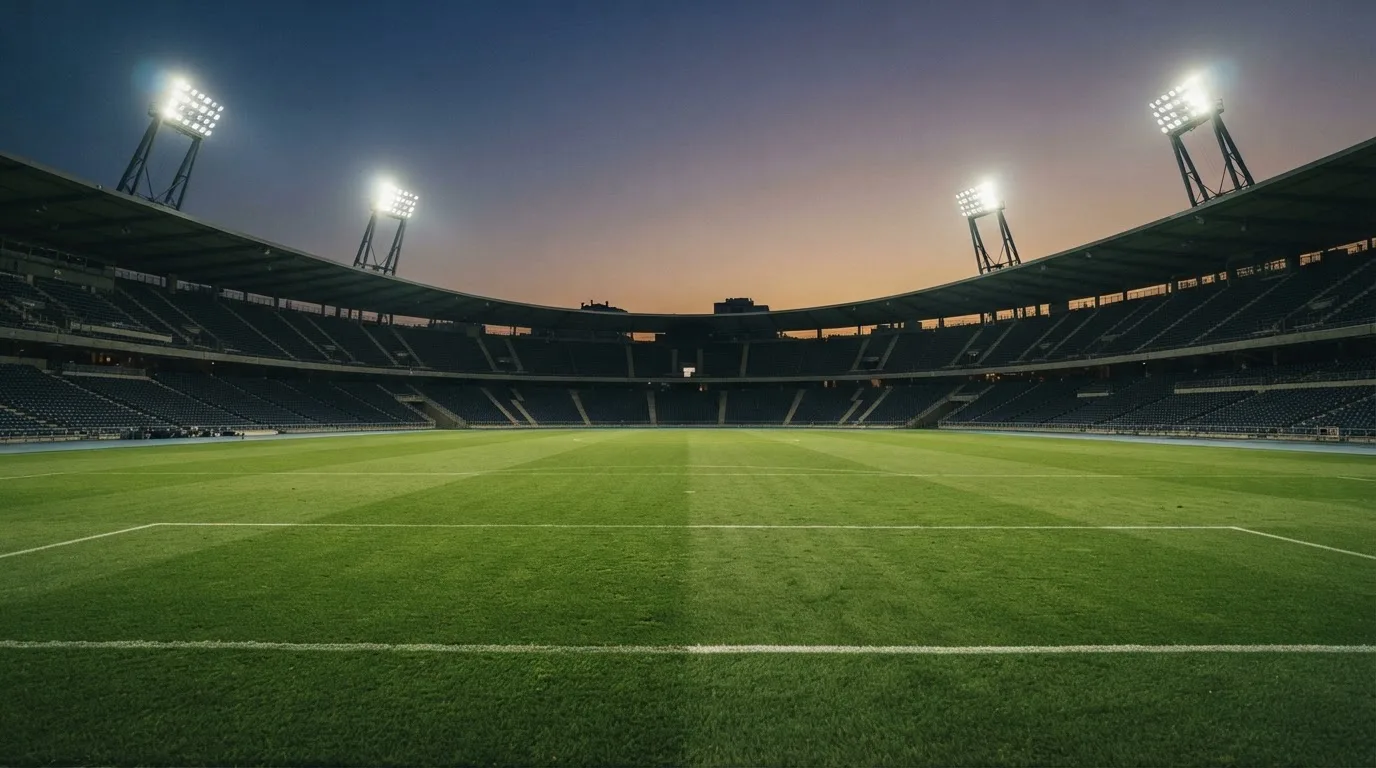 An empty football stadium with floodlight masts at dusk