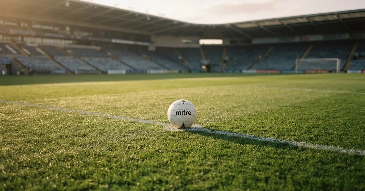 A ball on the centre spot of a grass pitch in morning light