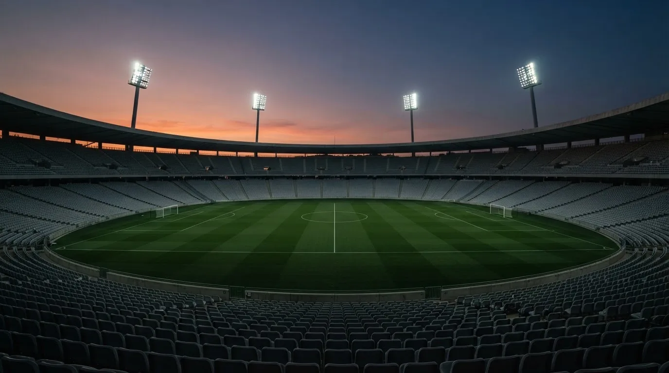 An empty football stadium with floodlight masts at dusk