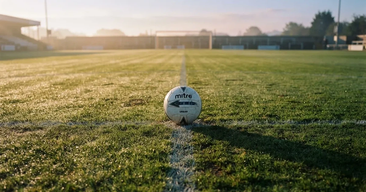 A ball on the centre spot of a grass pitch in morning light