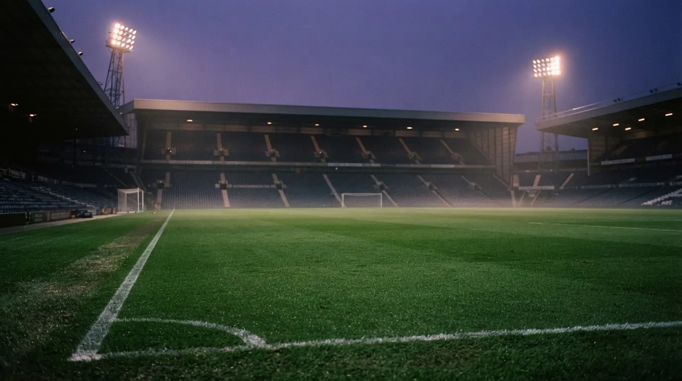 An empty football stadium with floodlight masts at dusk