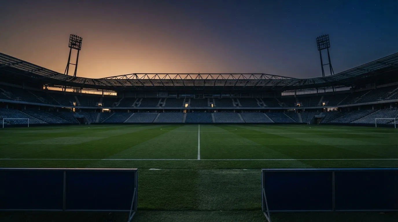 An empty football stadium with floodlight masts at dusk
