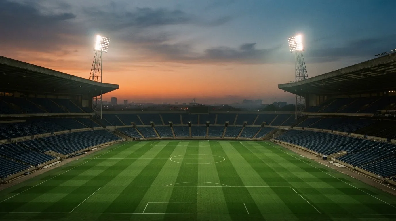 An empty football stadium with floodlight masts at dusk
