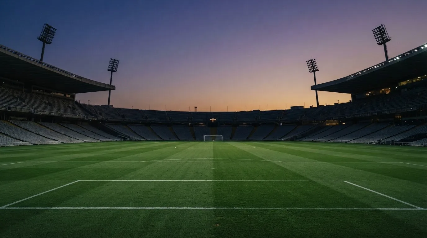 An empty football stadium with floodlight masts at dusk