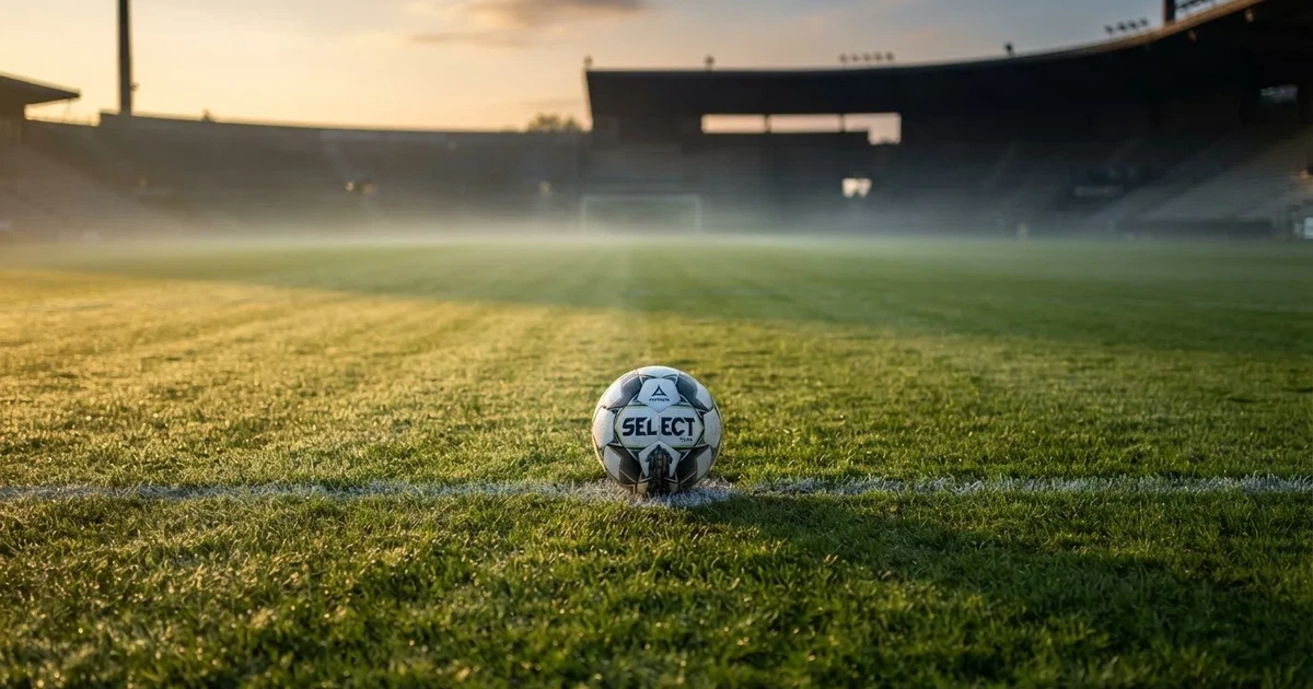 A ball on the centre spot of a grass pitch in morning light
